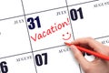 A hand writing a VACATION text and drawing a smiling face on a calendar date 31July. Vacation planning concept. Royalty Free Stock Photo