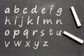 Hand written alphabet small letters and two chalk sticks placed on the blackboard. Royalty Free Stock Photo