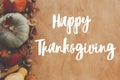 Hand written Happy Thanksgiving text on background of pumpkins, autumn leaves, nuts, harvest vegetables on rustic wood, flat lay. Royalty Free Stock Photo