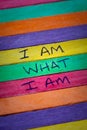 I am what I am hand lettering quote on a rainbow spectrum pride flag