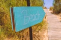 Hand written wooden sign pointing to the beach