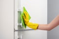 Hand in yellow glove cleaning white refrigerator with green rag Royalty Free Stock Photo