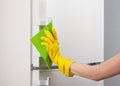 Hand in yellow glove cleaning white refrigerator with green rag Royalty Free Stock Photo