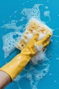 Hand in yellow glove holding sponge with foam. Cleaning concept. Royalty Free Stock Photo