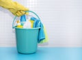 A hand in yellow glove holds bucket with detergents and cleaning accessories, rags gloves sponge brushes. Royalty Free Stock Photo