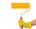 A hand in a yellow glove holds a yellow paint roller with a textured surface for wall decoration, on a white background Royalty Free Stock Photo