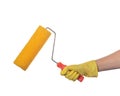 A hand in a yellow glove holds a yellow paint roller with a textured surface for wall decoration, on a white background Royalty Free Stock Photo