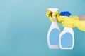 Hand in yellow glove holds spray bottle of liquid detergent on blue background. cleaning Royalty Free Stock Photo