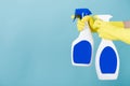 Hand in yellow glove holds spray bottle of liquid detergent on blue background. cleaning Royalty Free Stock Photo