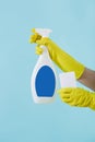 Hand in yellow glove holds spray bottle of liquid detergent and sponge on blue background. cleaning Royalty Free Stock Photo