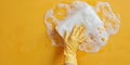 Hand in yellow glove pressing soapy sponge against yellow background, cleaning service banner, copy space Royalty Free Stock Photo