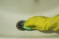 Hand in yellow glove with sponge cleaning white sink Royalty Free Stock Photo