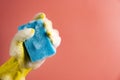 Hand in yellow glove with sponge in foam on pink background. Cleaning concept. Royalty Free Stock Photo