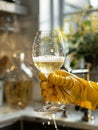 Hand in yellow gloves with champagne glass in kitchen. Royalty Free Stock Photo