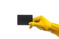 A hand in a yellow latex glove holds a black rectangular sheet of paper