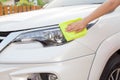Hand with yellow microfiber cloth cleaning big white car.