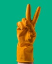 Hand with yellow protective rubber glove making peace sign Royalty Free Stock Photo