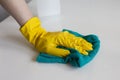 Hand in yellow rubber glove cleans table surface with a cloth. Cleanup at home