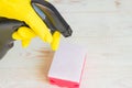 Hand in yellow rubber glove holding black plastic spray detergent bottle. Household chemicals. Cleaning product Royalty Free Stock Photo