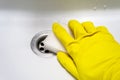 A hand in a yellow rubber glove with a melamine sponge rubs the wet white bath or the sink near the drain hole. Cleaning Royalty Free Stock Photo