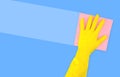 Hand in a yellow rubber glove with a pink cleaning sponge leaves a stripe on a blue background with a copy space Royalty Free Stock Photo