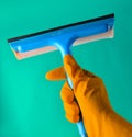 A hand with yellow rubber gloves holds a window mop on a blue Royalty Free Stock Photo