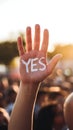 Hand with YES painted on palm, rally setting, radiates affirmation Royalty Free Stock Photo