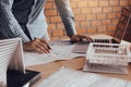 Hand of young engineering man drawing on blueprint with model on desk