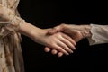 Handshake of two women, young and old, close-up. The hand of a young girl holds the hand of an elderly woman. Two hands, two Royalty Free Stock Photo