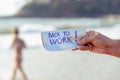 hand of a young man on the beach, in front of ocean in the background, holding paper with the text back Royalty Free Stock Photo