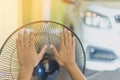 Hand of Young man touch and adjust on front grills of electric fan for a good wind in his home in summer of april