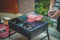 Young Man Grills Sliced beef on Charcoal Grill.