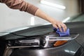 Hand of young man worker of auto service, wiping and polishing the headlights and hood