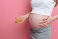 Hand of a young pregnant woman holding blister packs of pills. Reception of vitamins during pregnancy. on a pink background Royalty Free Stock Photo
