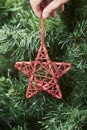 Hand of a young woman hanging a red decorative star on a Christmas tree Royalty Free Stock Photo