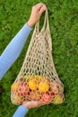 A hand of young woman hold fruits and vegetables in an eco-friendly string