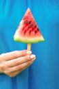 Hand of young woman is holding piece of watermelon like ice cream on a green nature background