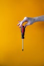 Hand of a young woman holding a screwdriverhand of a young woman holding a screwdriver, red nail polish on nails Royalty Free Stock Photo