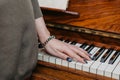 The hand of a young woman lies on the keys of a piano
