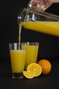 The hand of a young woman pours orange juice from a jug into a glass Royalty Free Stock Photo