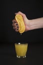 Hand of a young woman squeezes juice from an orange into a glass Royalty Free Stock Photo