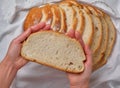 Hand of young woman takes a piece of homemade rustic bread