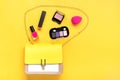 Handbag, set of professional decorative cosmetics, black makeup tools and accessory of trendy pink color on yellow background Royalty Free Stock Photo