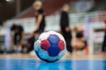 Handball ball on court` s floor. Blurred referees, coaches and athletes and field background. Royalty Free Stock Photo