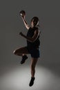 Handball player posing on gray background. Girl jumping with ball Royalty Free Stock Photo