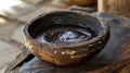 A handcarved wooden bowl is filled with a dark sticky paste. This mixture is made from various plants and minerals and