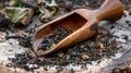 A handcarved wooden tea scoop resting on a pile of dried tea leaves