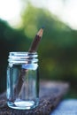 Handcraft pencil made of wood in glass bottle with smooth blur green garden background