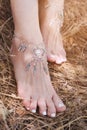 Handcrafted bracelets on a woman legs, close up, white pedicure