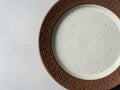 Handcrafted ceramic plate with textured brown rim on light surface Royalty Free Stock Photo
